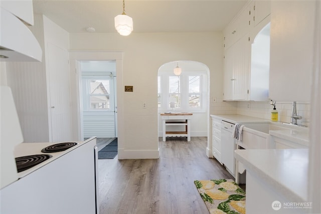 kitchen featuring arched walkways, white cabinetry, light wood-style flooring, and a healthy amount of sunlight
