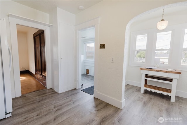 hallway featuring baseboards, arched walkways, and wood finished floors