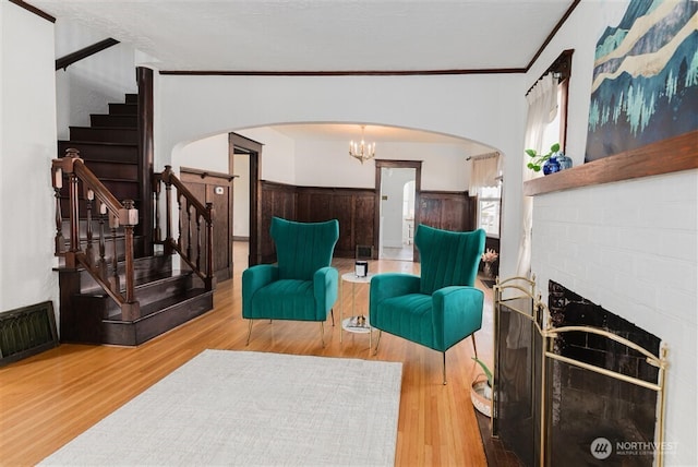 living area with a wainscoted wall, visible vents, stairs, wood finished floors, and arched walkways