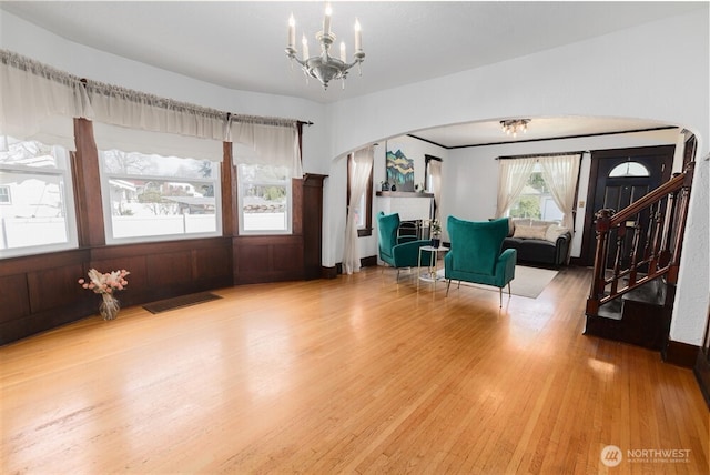 living area with stairway, wood finished floors, visible vents, arched walkways, and an inviting chandelier
