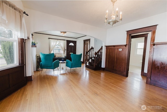 sitting room featuring light wood-style flooring, arched walkways, stairway, and a chandelier