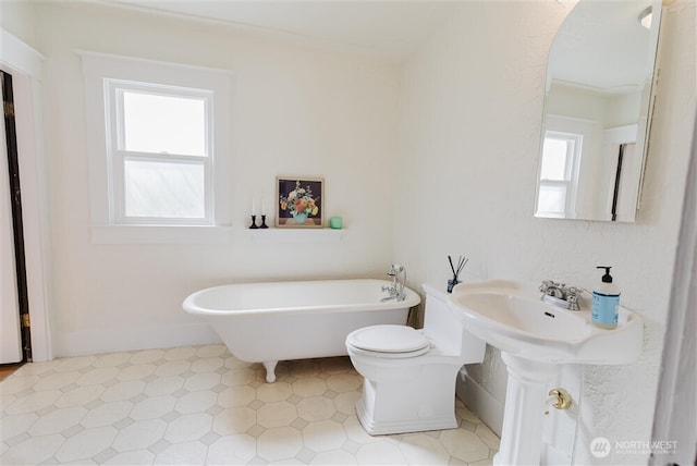 full bath with a soaking tub, baseboards, plenty of natural light, and toilet