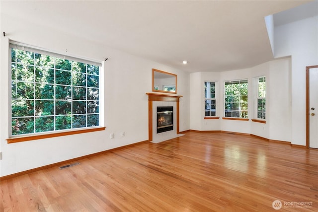 unfurnished living room featuring baseboards, visible vents, wood finished floors, and a tile fireplace