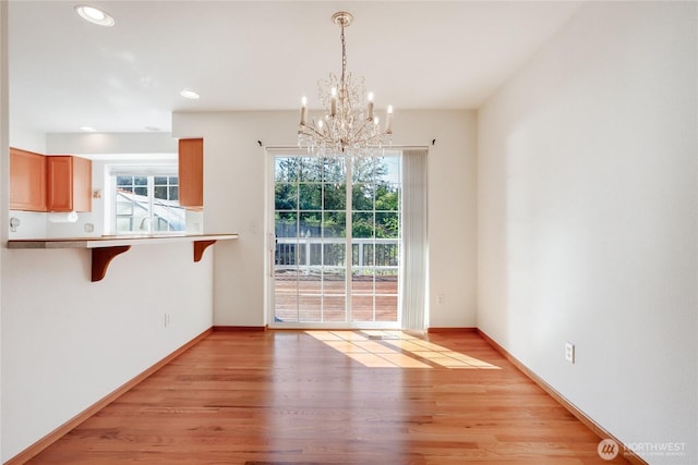 unfurnished dining area featuring light wood finished floors, baseboards, a notable chandelier, and recessed lighting