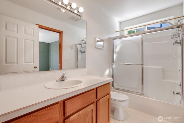 bathroom featuring combined bath / shower with glass door, toilet, and vanity