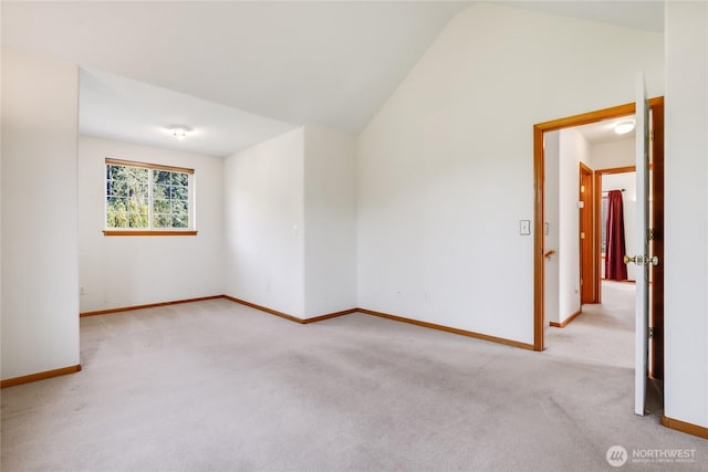 carpeted empty room with baseboards and lofted ceiling