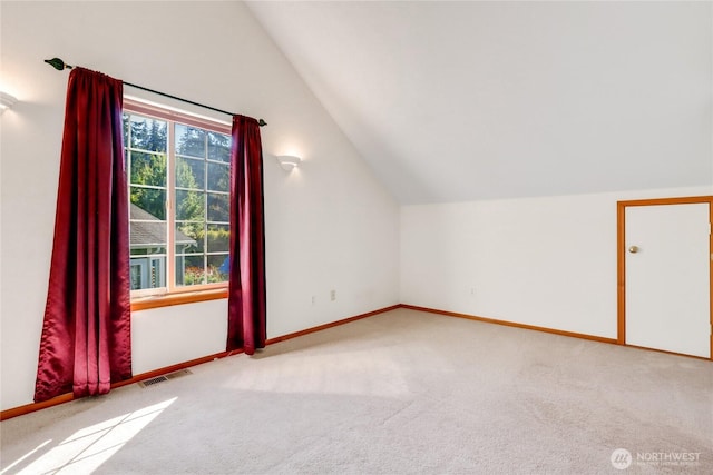 additional living space with baseboards, carpet floors, visible vents, and vaulted ceiling