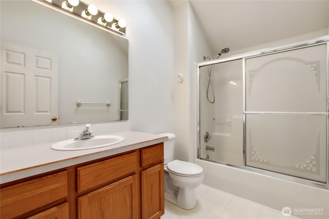 full bath featuring combined bath / shower with glass door, toilet, tile patterned flooring, and vanity