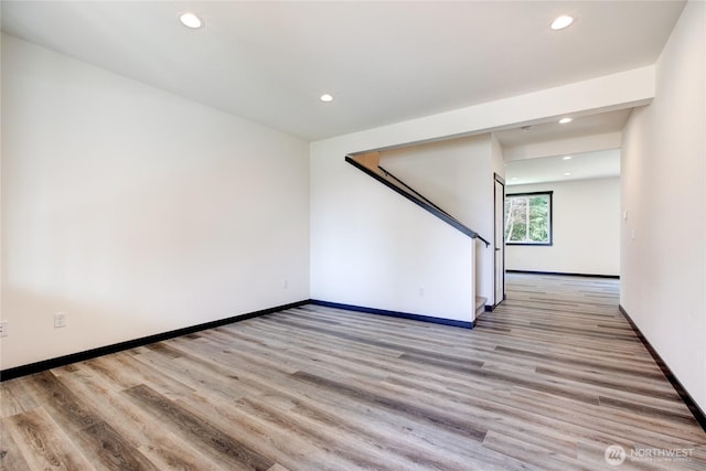unfurnished living room with recessed lighting, light wood finished floors, baseboards, and stairway