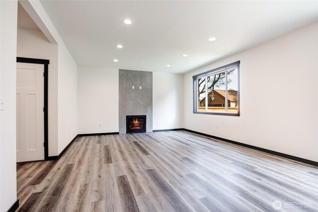 unfurnished living room featuring a fireplace, recessed lighting, baseboards, and light wood-style floors