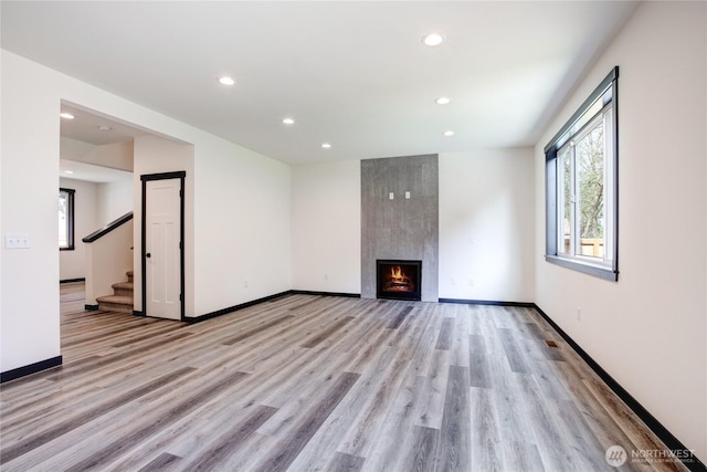 unfurnished living room with recessed lighting, baseboards, stairway, and light wood-type flooring