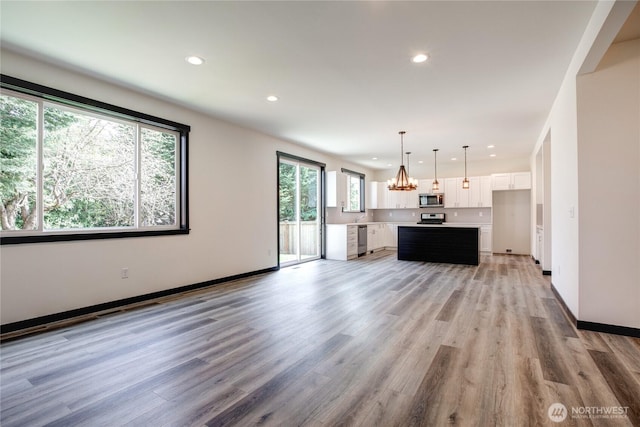 unfurnished living room featuring recessed lighting, baseboards, a chandelier, and light wood-style floors