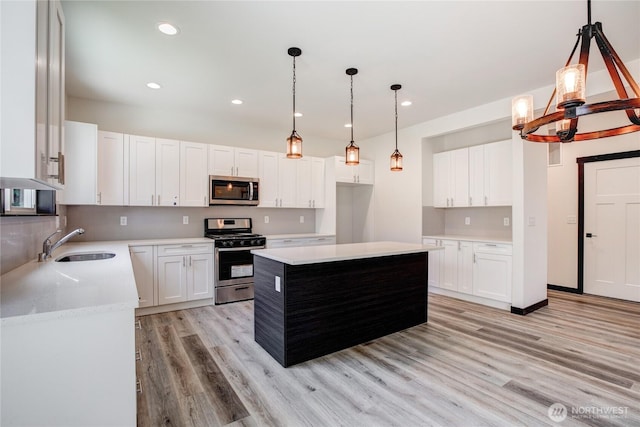 kitchen featuring appliances with stainless steel finishes, light wood-type flooring, a sink, light countertops, and recessed lighting