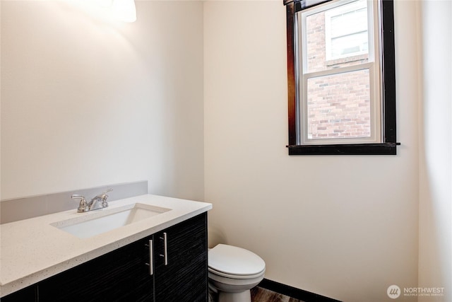 half bathroom with vanity, toilet, and wood finished floors
