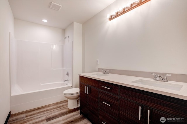 bathroom featuring a sink, toilet, wood finished floors, and visible vents
