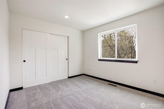 unfurnished bedroom featuring a closet, baseboards, carpet flooring, and visible vents
