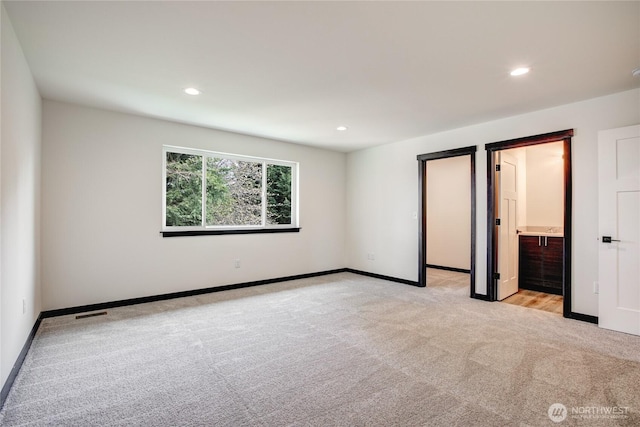 unfurnished bedroom with baseboards, recessed lighting, connected bathroom, and light colored carpet