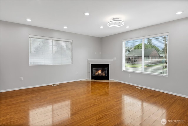 unfurnished living room with wood finished floors, baseboards, and visible vents