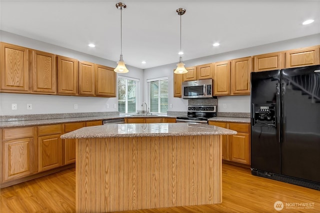 kitchen featuring a kitchen island, a sink, stainless steel appliances, and light wood-type flooring