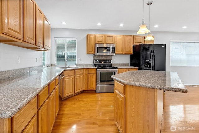 kitchen with a kitchen island, a kitchen bar, appliances with stainless steel finishes, light wood-type flooring, and recessed lighting