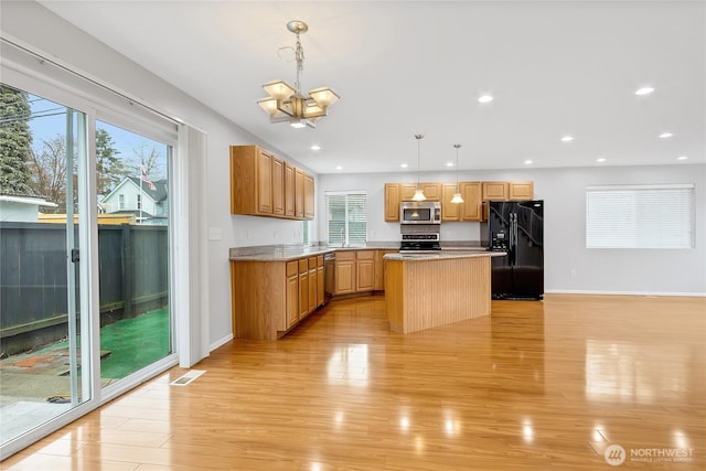 kitchen with recessed lighting, stainless steel appliances, hanging light fixtures, a kitchen island, and light wood-style floors