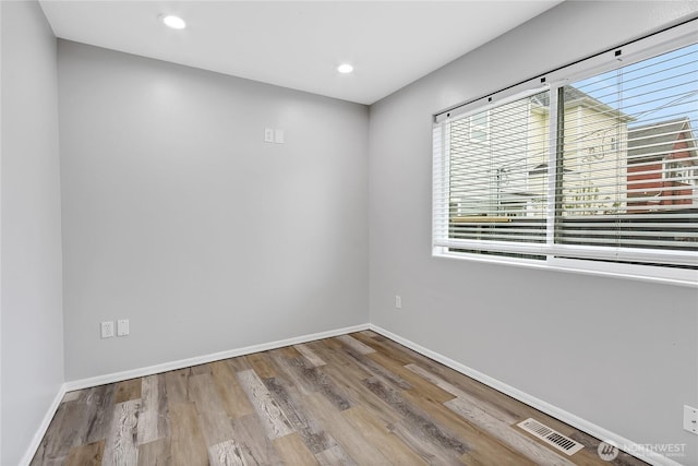 empty room with baseboards, visible vents, wood finished floors, and recessed lighting