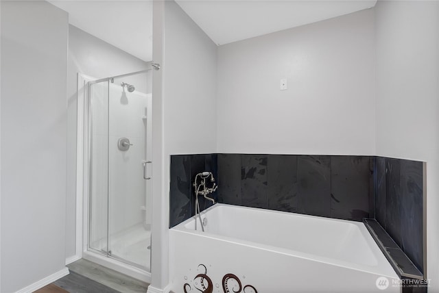 full bath featuring wood finished floors, a garden tub, and a stall shower
