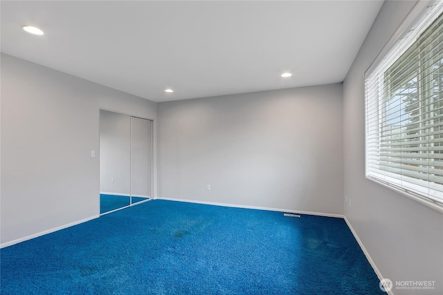 unfurnished bedroom featuring baseboards, carpet flooring, a closet, and recessed lighting