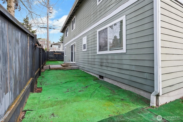 view of side of property featuring a lawn, entry steps, and fence