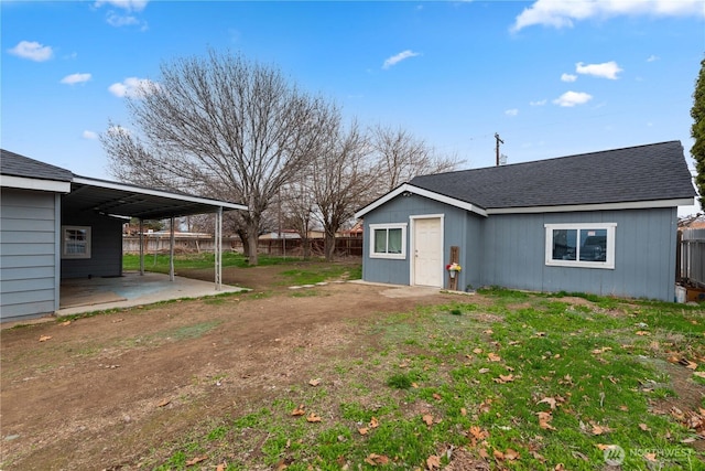 view of yard featuring a carport, fence, and dirt driveway