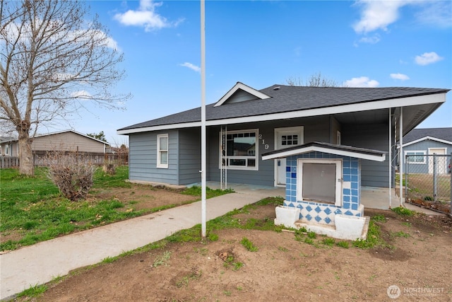 bungalow-style home featuring roof with shingles and fence