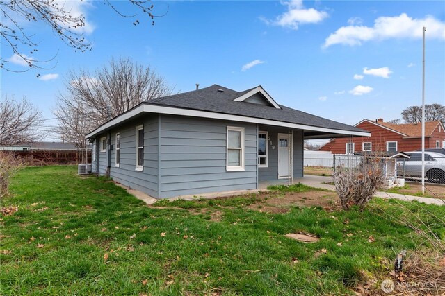 bungalow-style home with central AC unit, fence, and a front lawn