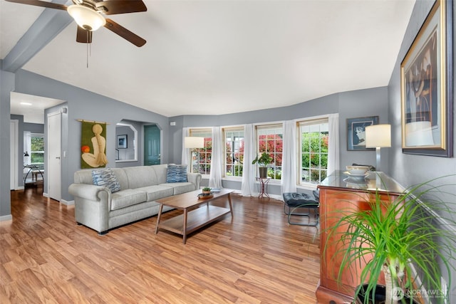 living area with light wood-type flooring, baseboards, lofted ceiling, arched walkways, and ceiling fan