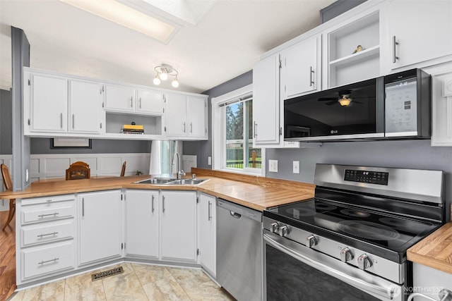 kitchen featuring stainless steel appliances, white cabinetry, a sink, and open shelves