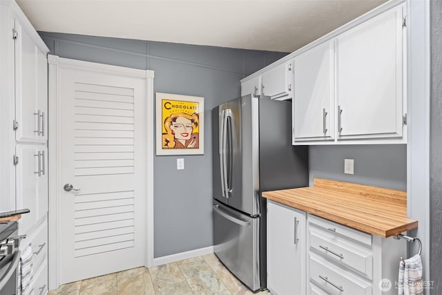 kitchen featuring wood counters, baseboards, white cabinetry, and stainless steel appliances