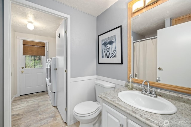 full bathroom with washer and clothes dryer, vanity, a textured ceiling, and toilet