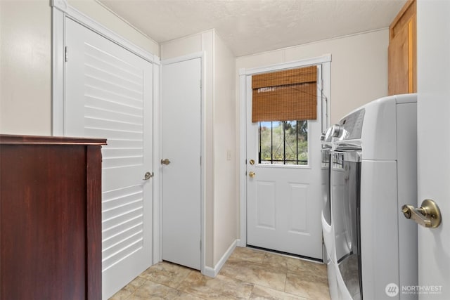 clothes washing area with laundry area, baseboards, and washing machine and dryer