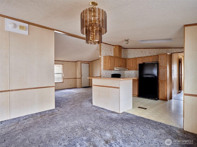 1850 Heartwood Dr, Woodland, WA 98674 - kitchen with under cabinet range hood, a chandelier, wallpapered walls, freestanding refrigerator, and light floors