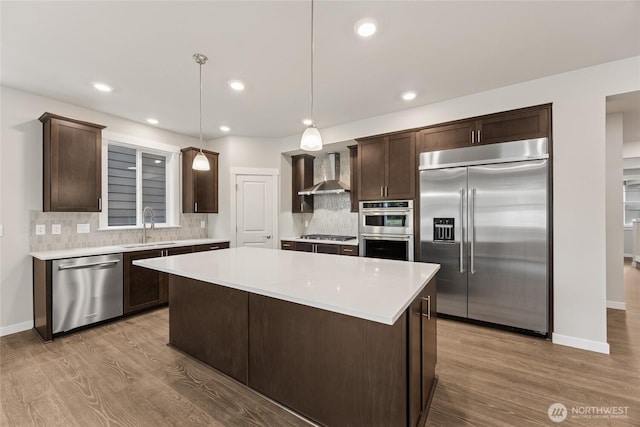 11519 SE 84th St Unit 44, Newcastle, WA 98056 - kitchen with stainless steel appliances, wall chimney exhaust hood, dark brown cabinetry, wood finished floors, and backsplash