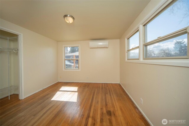 708 S Park Pl, Ellensburg, WA 98926 - unfurnished bedroom with baseboards, a closet, a wall mounted AC, and wood finished floors