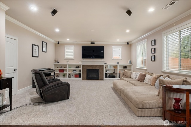 living room featuring visible vents, carpet floors, ornamental molding, and a glass covered fireplace