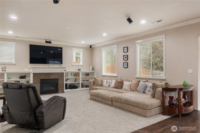 living room featuring recessed lighting, visible vents, a glass covered fireplace, and crown molding
