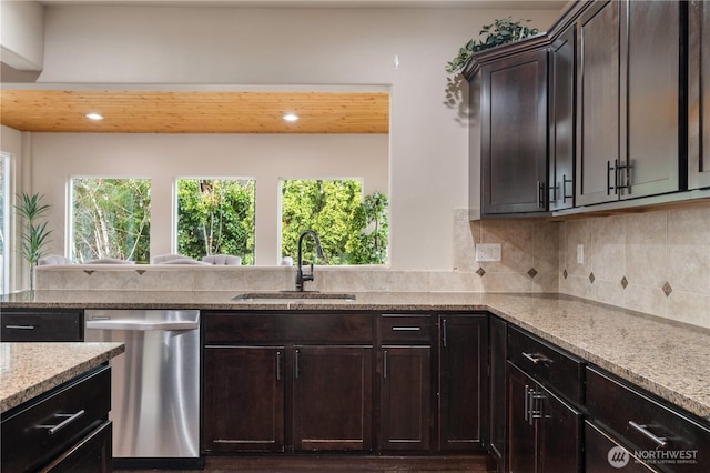kitchen with backsplash, a sink, dishwasher, light stone countertops, and dark brown cabinets