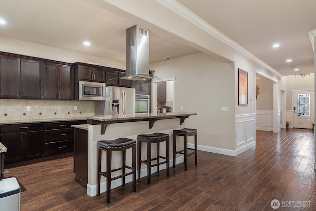 kitchen featuring island exhaust hood, dark wood-style flooring, a breakfast bar, and stainless steel appliances