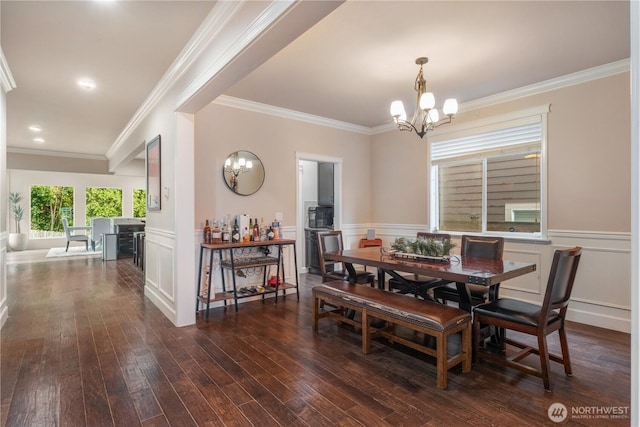 dining room with a notable chandelier, crown molding, wainscoting, a decorative wall, and dark wood-type flooring