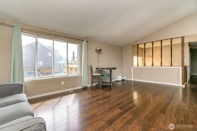 living area with baseboards, lofted ceiling, visible vents, and wood finished floors