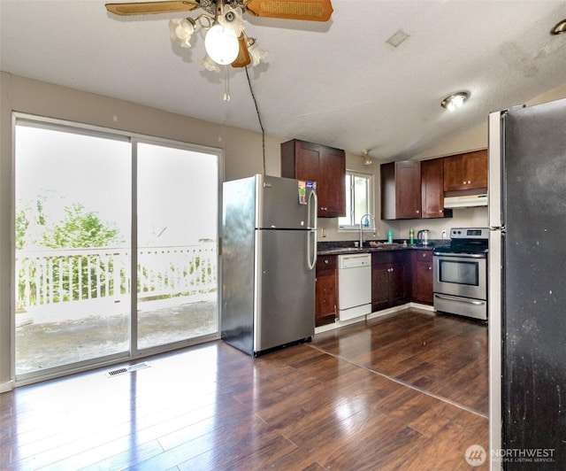kitchen featuring stainless steel appliances, under cabinet range hood, a sink, dark countertops, and visible vents