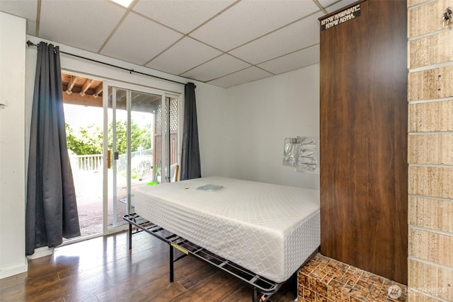 bedroom featuring wood finished floors, a paneled ceiling, and access to outside