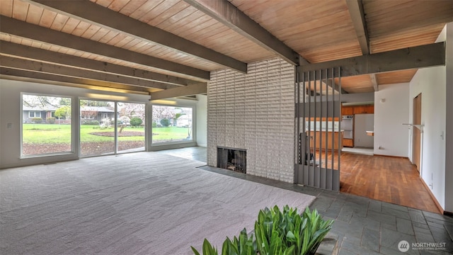 unfurnished living room featuring baseboards, a fireplace, wood ceiling, and beam ceiling