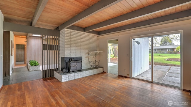 unfurnished living room featuring a healthy amount of sunlight, a wood stove, and wood finished floors